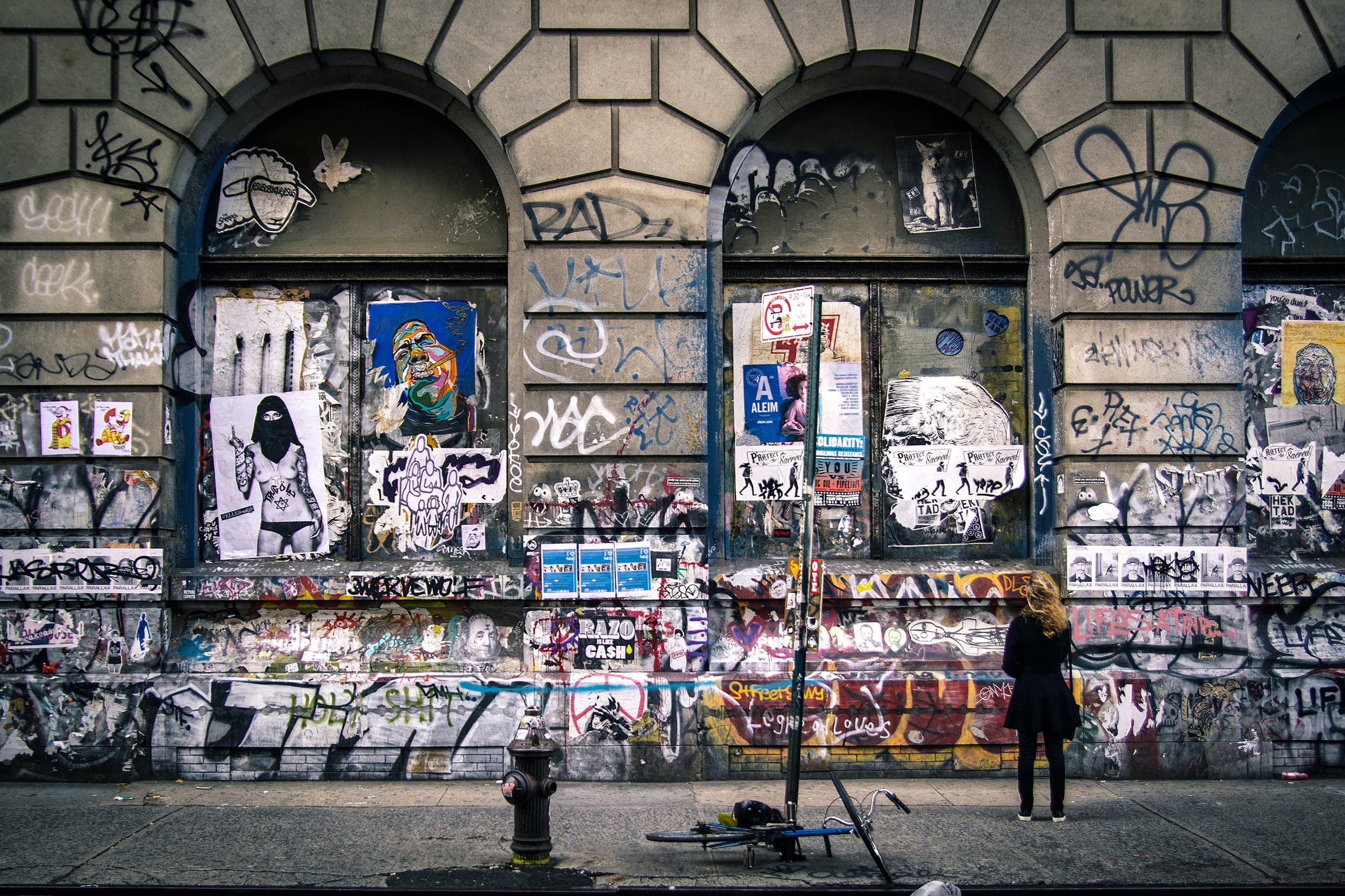 Graffiti-covered building facade with arched windows and street art